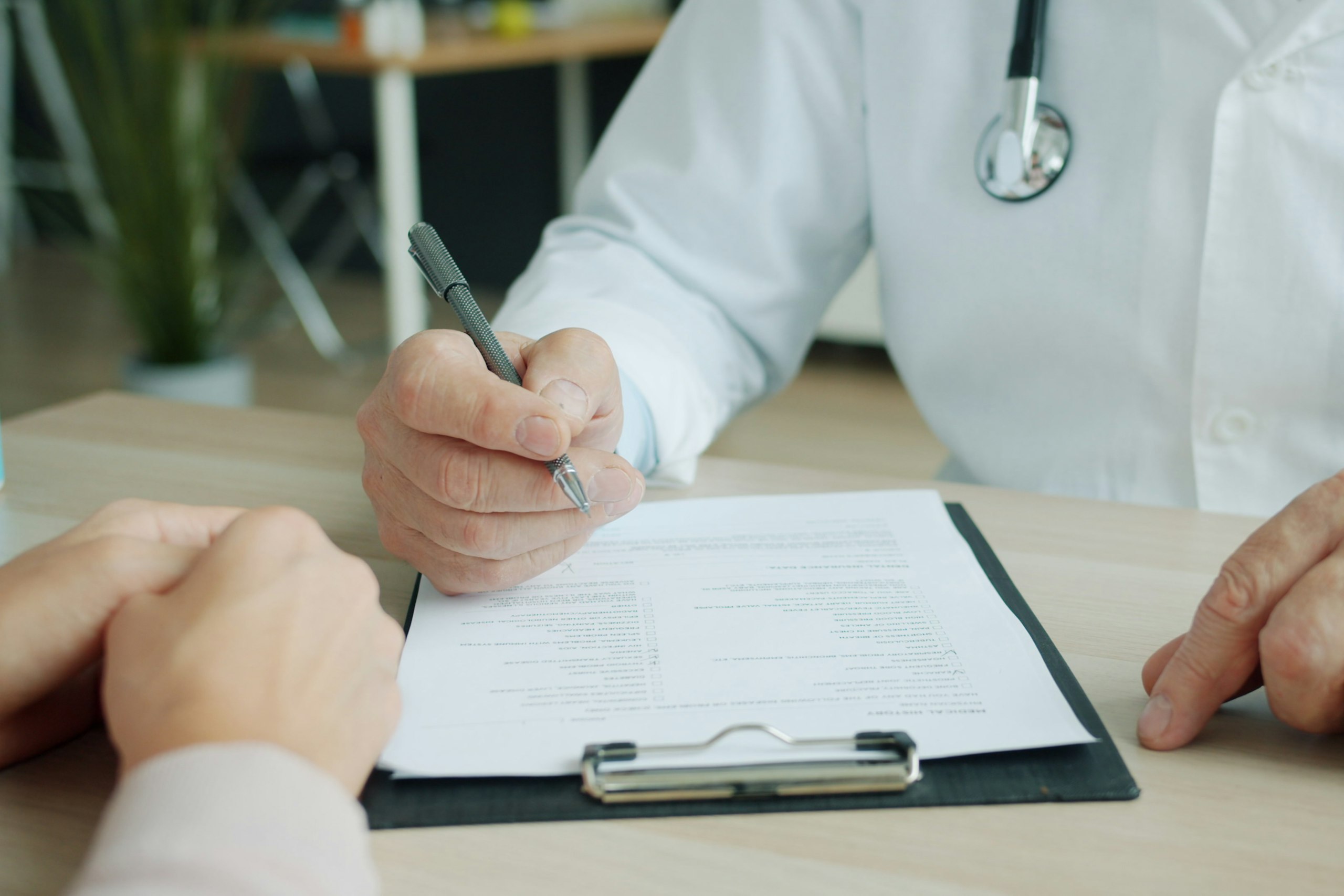 Arzt notiert Befunde im Patientengespräch
